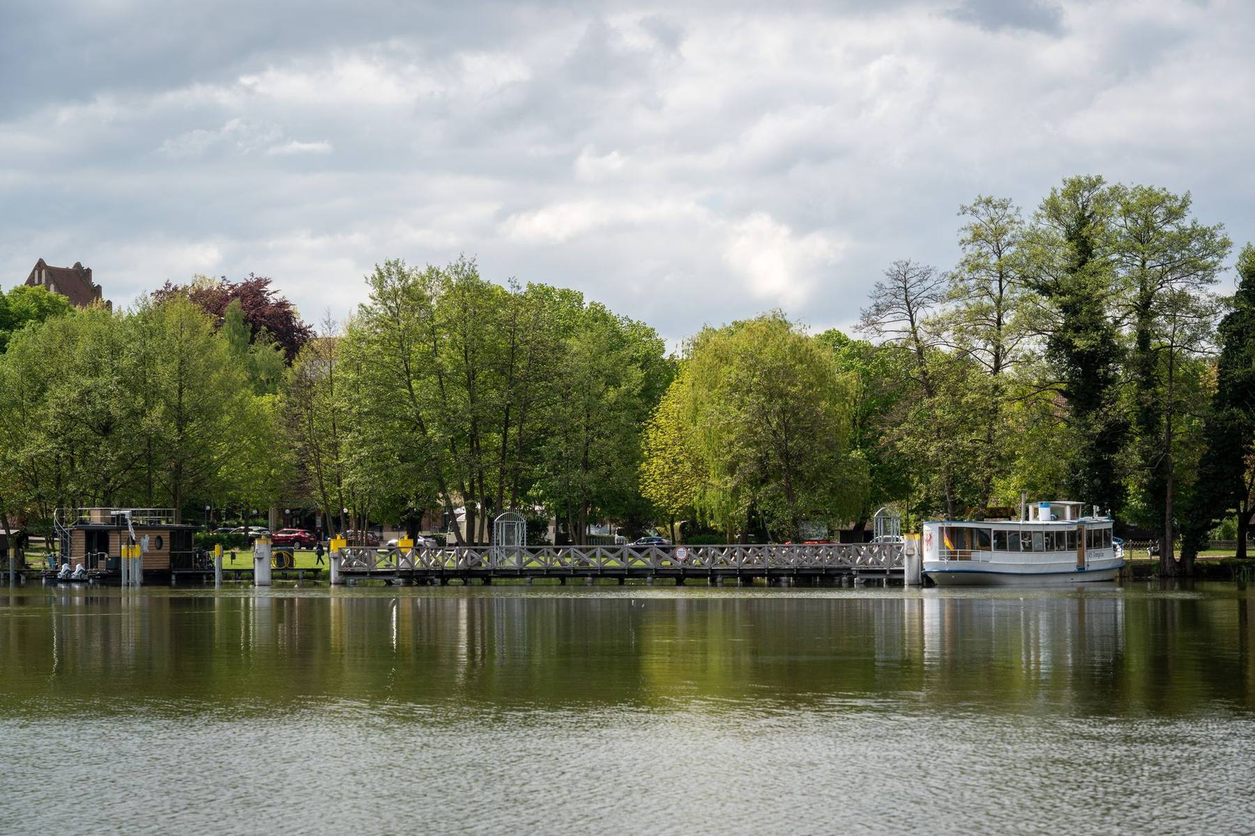 Calm tree-lined lake with a small boat at golden hour
